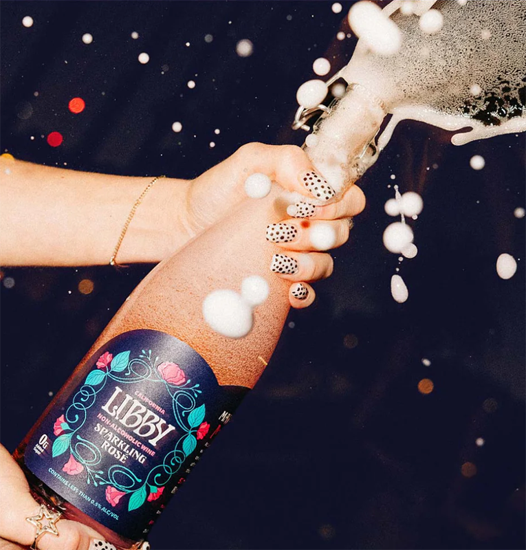 Hands popping a bottle of Libby Non Alcoholic Wine