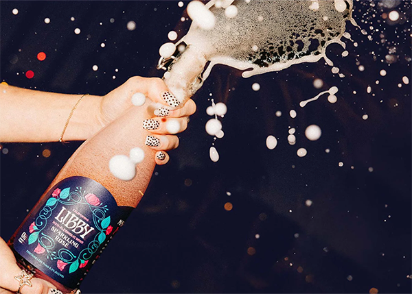 Hands popping a bottle of Libby Non Alcoholic Wine